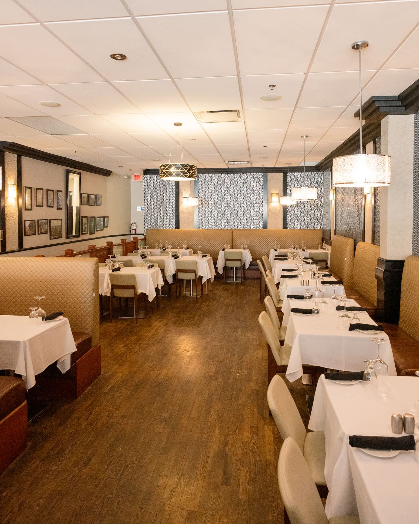 Salle à manger : banquettes capitonnées beiges, tables nappées de blanc et suspensions
